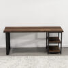 The Loredo Desk is a minimalist piece, boasting a wooden surface complemented by a sleek black metal frame. It features a flat rectangular top with two open shelves on the right side. Positioned against a plain white wall and set atop a light gray patterned rug, the desk adds chic functionality to any space.