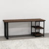 The Loredo Desk is a modern, minimalist console table that features a dark wooden top and black metal legs, making it ideal office furniture. It includes two open shelves on the right side, perfect for creating an organized workspace. The desk stands on a light-colored floor against a white wall with a patterned rug visible in the foreground.