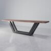 The Addison Bench boasts a sleek, elongated design that seamlessly combines modern aesthetics with functionality. It features a wooden surface mounted on a geometric, black metal frame base arranged in an eye-catching V-shape. The bench is presented against a minimalist, light-toned background, further enhancing its contemporary appeal.