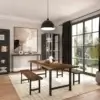 Modern dining room with a Black Walnut Live Edge Table with H-shaped Legs and matching benches featuring sleek black metal legs. The room has a large window with black curtains, a black-framed glass cabinet, abstract wall art, and a hanging black pendant light. The floor is hardwood with a beige rug underneath the table.