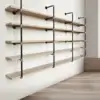The Industrial Hanging Pipe Shelf, with its five wooden shelves supported by black metal brackets, introduces an industrial flair to the space. The shelves are spaced evenly and aligned horizontally against a white wall. With a light wood floor, the room appears modern and tidy.