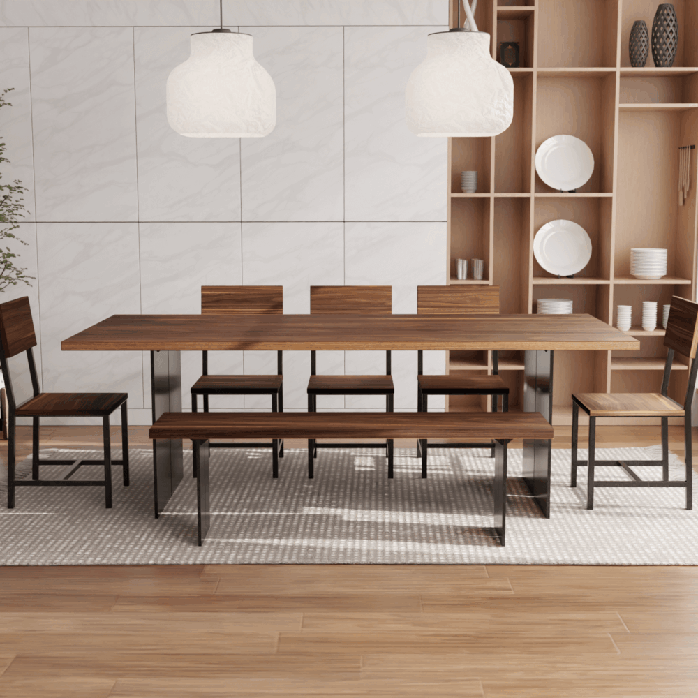 A contemporary dining room showcases The Steel Bennett Dining Table, accompanied by four chairs and a bench with sleek black metal frames. Suspended above the table are two elegant white pendant lights. In the background, shelving displays an array of white plates and decorative items. To the left of the scene, a potted plant adds a touch of greenery on a beautiful hardwood floor.