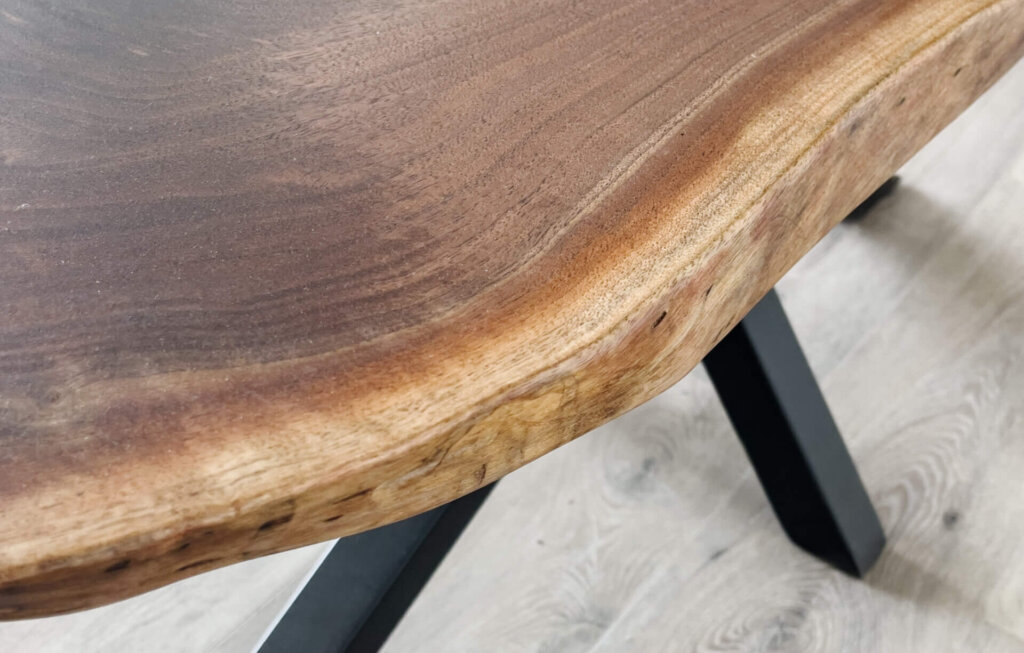 A close-up of the Ready To Ship - Black Walnut Live Edge Coffee Table, highlighting its natural wood grain and organic shape. The table features black metal legs and is set on a light-colored wood floor, perfect for instant style enhancement.