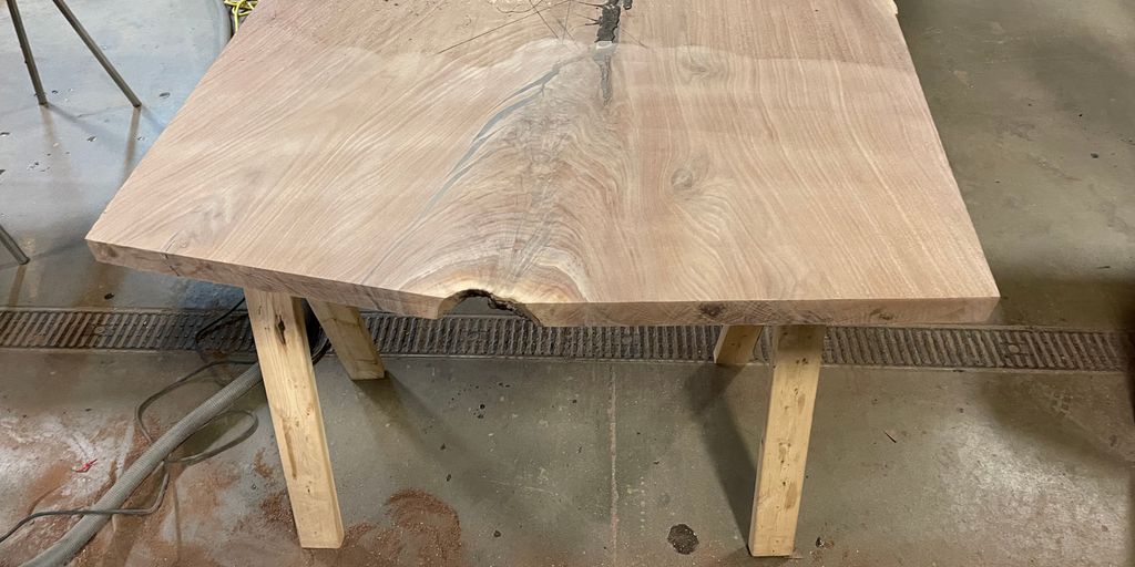 A large wooden table with natural imperfections and rustic legs.